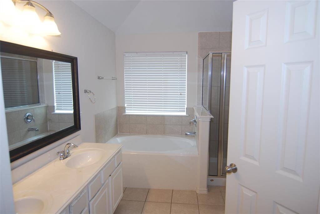 Primary bath with double sinks, soaking tub, separate shower, and private commode.