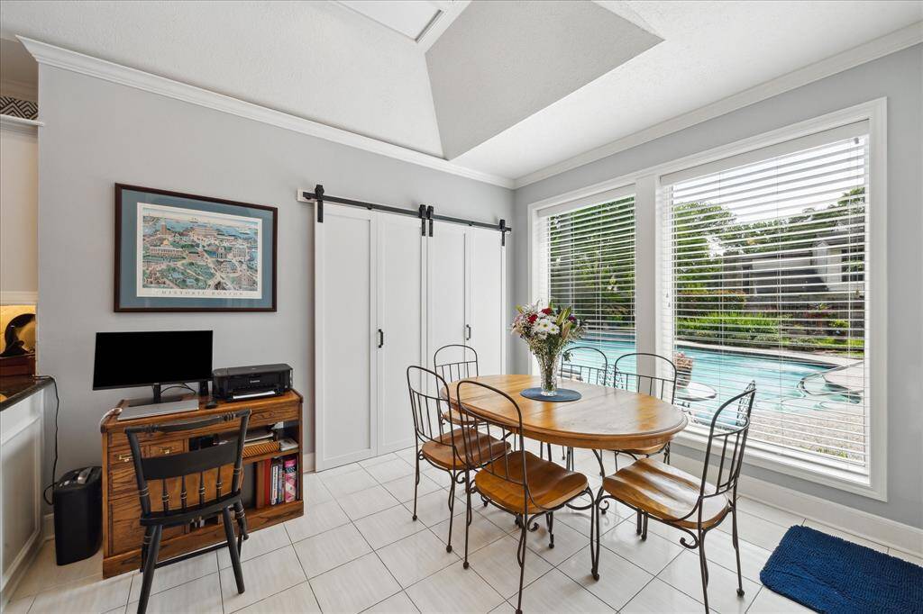 The breakfast area features large windows overlooking the pool and patio. Double doors at the rear of this photo provide access to the laundry.
