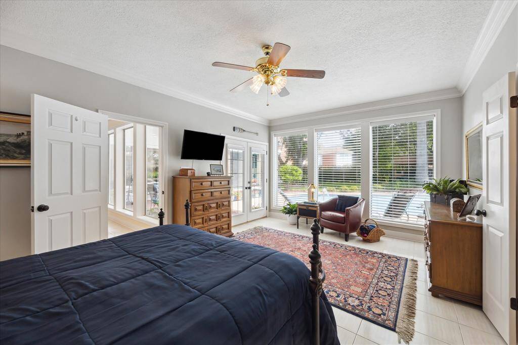 The primary bedroom has French door access to the patio and pool. The sitting area at the rear of the bedroom has triple windows overlooking the back yard.