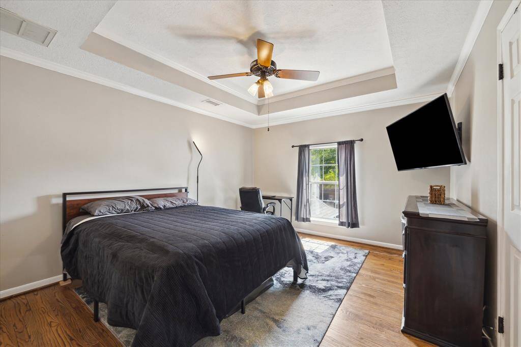 Upper level bedroom 2 has a coffered ceiling with crown molding and hardwood floor.