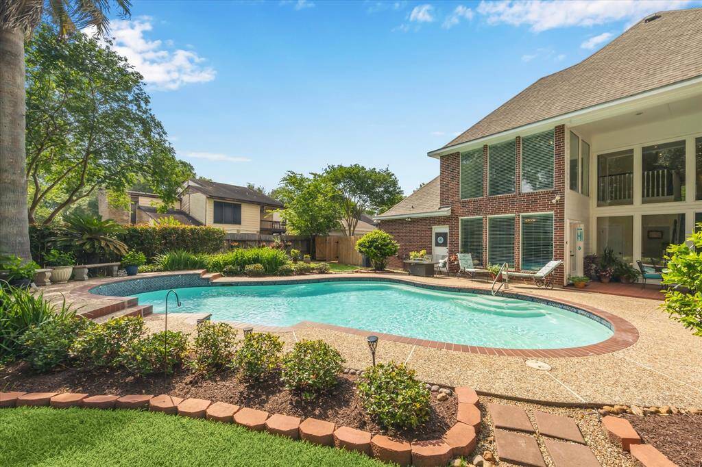 This view over the pool toward the rear of the home shows the numerous windows that overlook the pool and backyard.