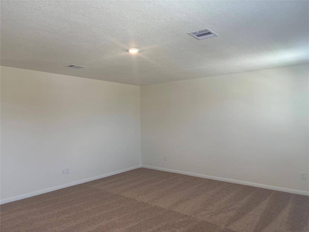 This photo shows a clean, game room with neutral-color walls and carpet, recessed lighting, and ceiling vents, offering a blank canvas for customization.