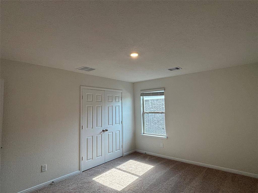 This secondary room upstairs features neutral walls, a single window allowing natural light, and a double-door closet. The carpeted floor adds warmth, and the ceiling light provides ample illumination. Perfect for a cozy bedroom or home office.