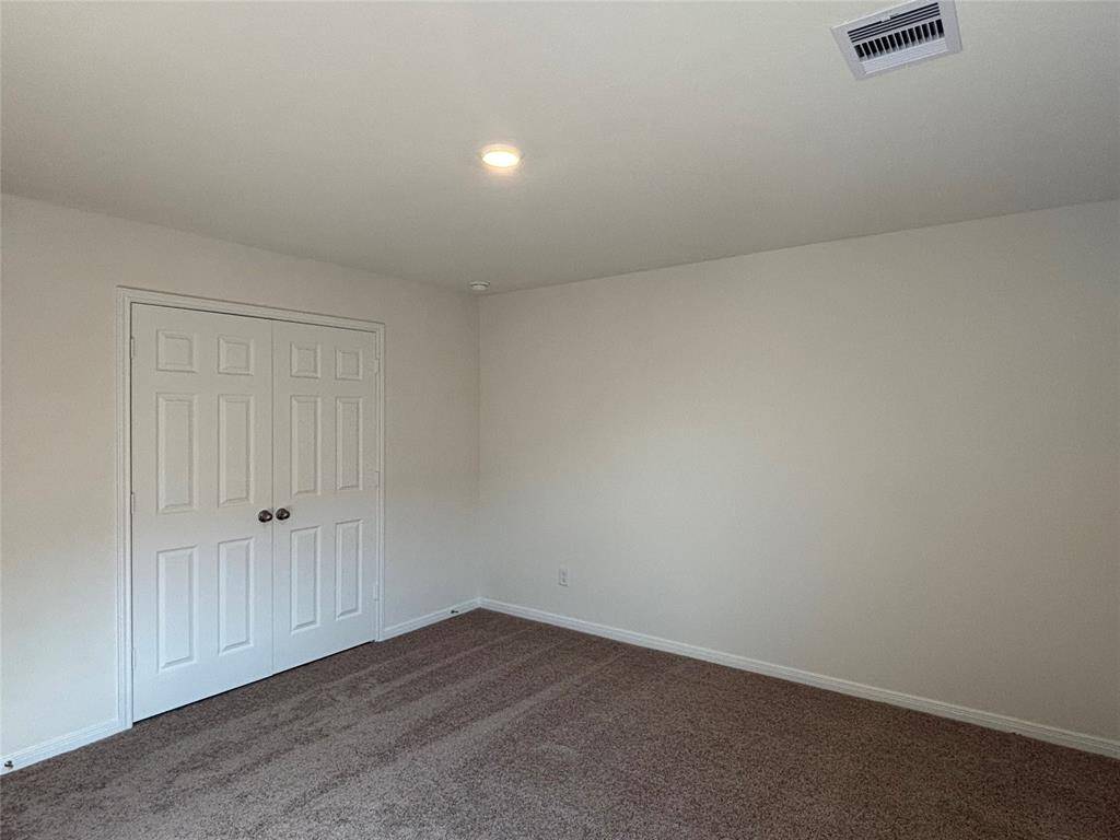 This fourth room upstairs features a neutral color palette with carpeted flooring and a double-door closet, offering a cozy and versatile space.