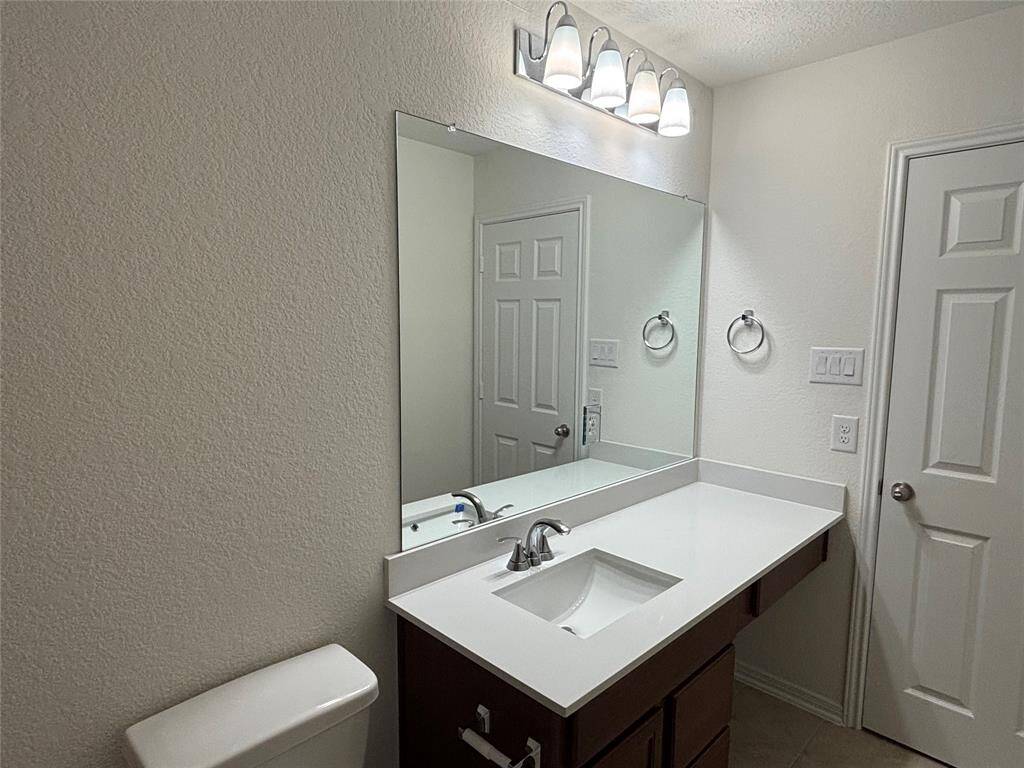 This secondary bathroom features a sleek and modern design with a large mirror, bright lighting, and a single-sink vanity with ample counter space. The neutral tones provide a clean and inviting atmosphere.