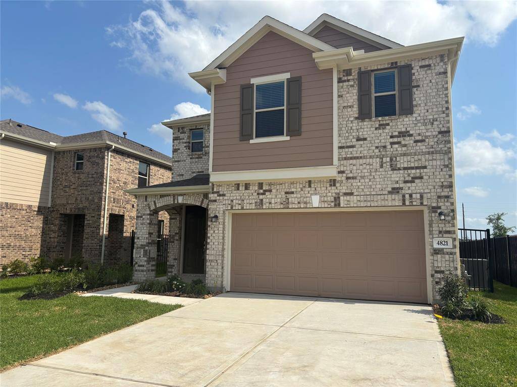 This is a modern two-story brick home with a two-car garage and a well-maintained front yard. It features a combination of light and dark brickwork with a covered entryway, offering a welcoming and stylish exterior.