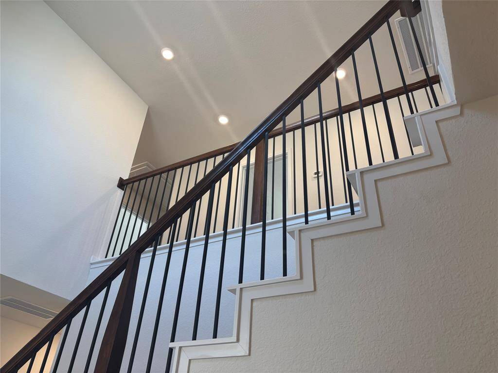 This photo showcases a modern staircase with sleek black railings and wooden accents. The space is well-lit with recessed ceiling lights, highlighting the clean, contemporary design and open feel.