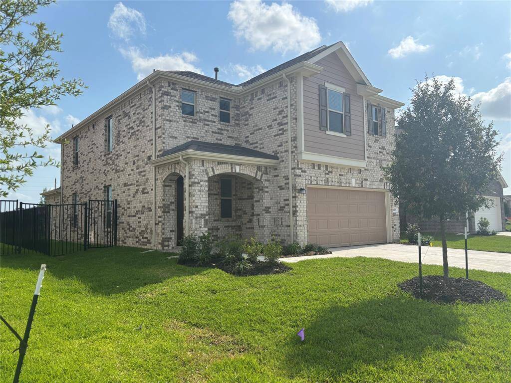This is a two-story, brick home with a modern design featuring a two-car garage. It has a well-maintained lawn and landscaping, and is located on a corner lot with a fenced yard.