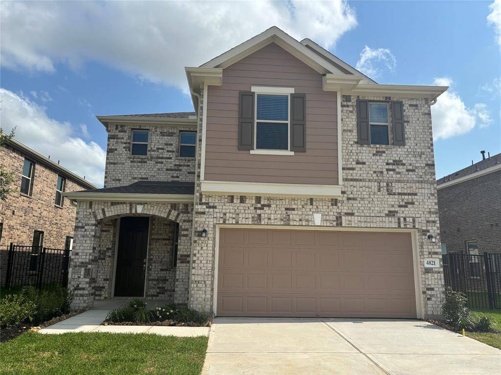 This is a two-story home with a modern brick exterior featuring an attached two-car garage. The facade includes a mix of brickwork and siding, with a welcoming front entryway and neatly landscaped front yard.