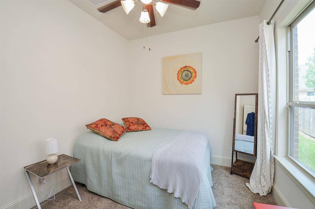 Bright light fills a carpeted secondary bedroom, perfect for family or visiting guests.