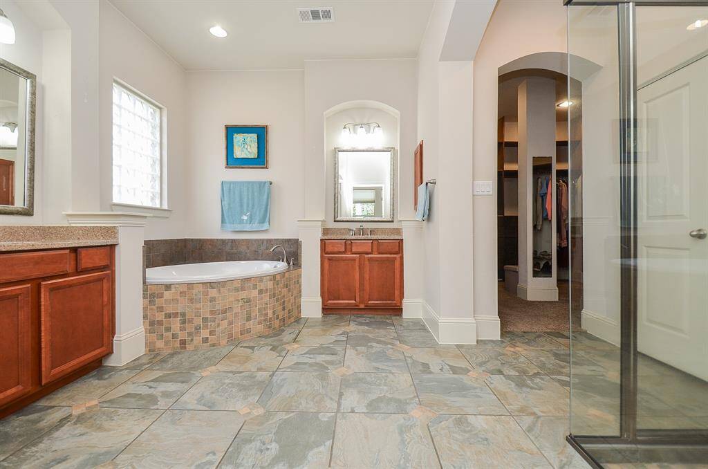 Streamlined and satisfying, your primary ensuite bath features dual/separate sinks, a cozy, mosaic/tile surround corner tub, wide open floor paths, and easy access to the walk-in closet, up right.