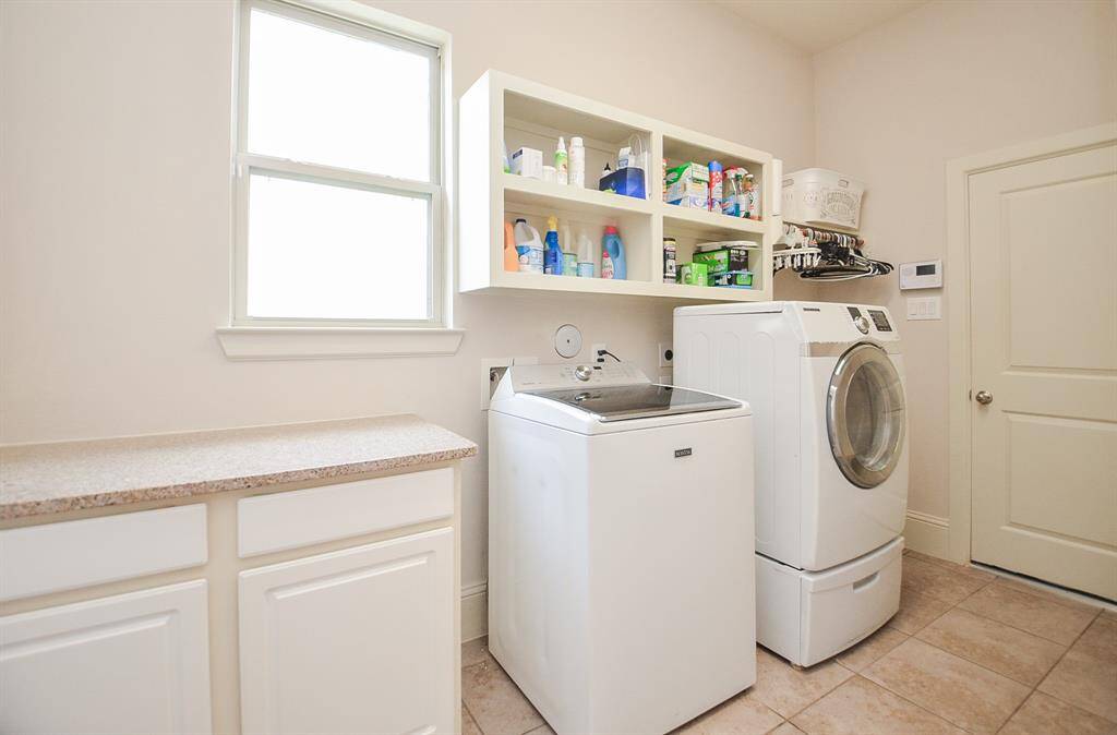 This spacious utility room easily hosts dual laundry appliances, with handy storage above; counter and storage space (left), and a welcomed window for balmy breezes.
