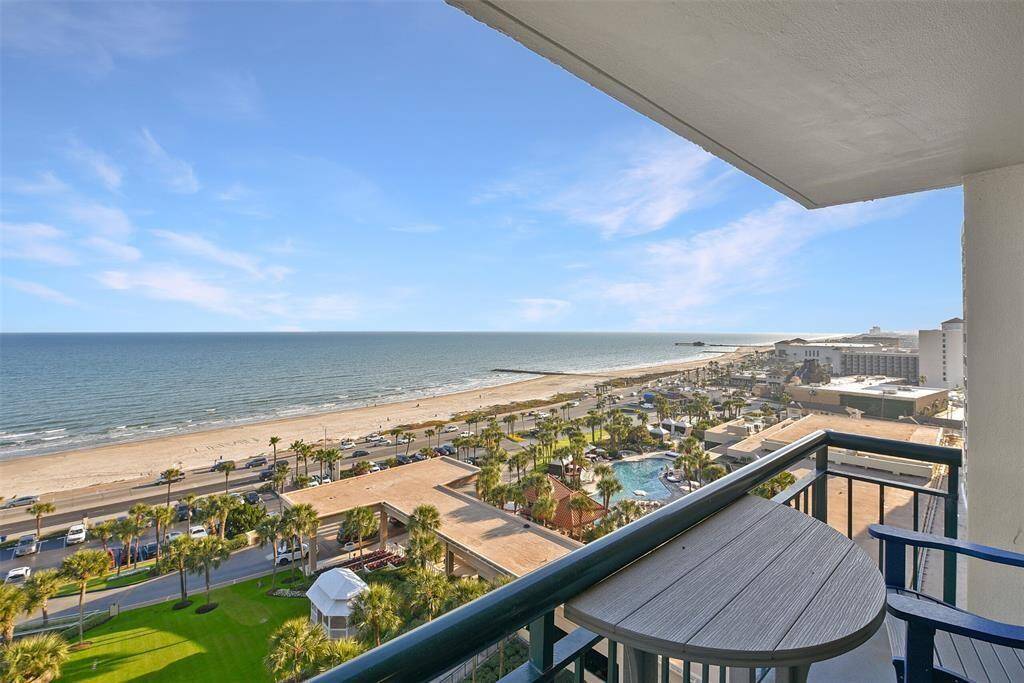 This photo showcases a balcony view from this 12th floor high-rise apartment, featuring a stunning oceanfront panorama, palm-lined promenade, and beach access
