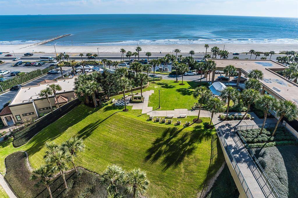 This is a high-angle view of a beachfront property with manicured lawns, palm trees, and direct access to the beach. The San Luis Resort is a well-maintained community spaces and is adjacent to the San Luis Hotel