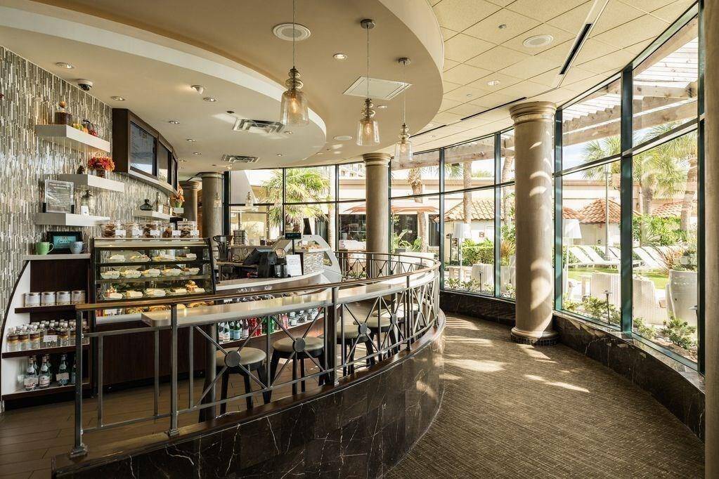 Cup n Cone cafe  with a sleek bar counter, a display of delectable pastries, and comfortable seating by large windows offering a beautiful view to enjoy your favorite Starbucks coffee