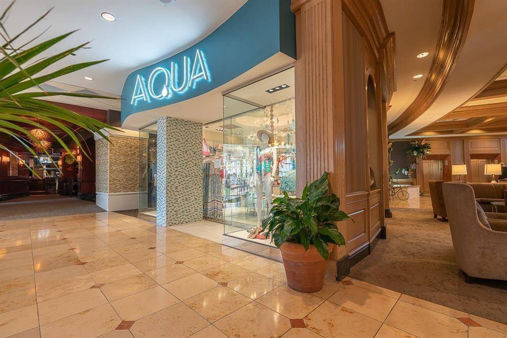 Luxurious interior lobby area featuring a polished marble floor, elegant archways, and plush seating. One of three stores, "AQUA", is featured here.