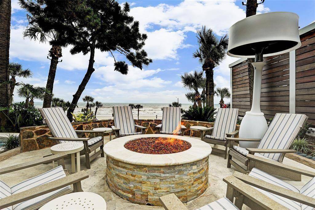 This is an inviting outdoor space featuring a cozy fire pit with surrounding Adirondack chairs, offering a stunning ocean view, ideal for relaxation and entertainment.