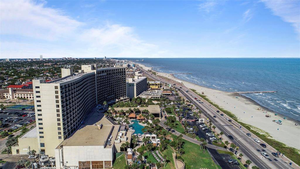 This is an aerial view of a high-rise building located directly next to a beach, offering expansive ocean views and proximity to beachfront amenities.