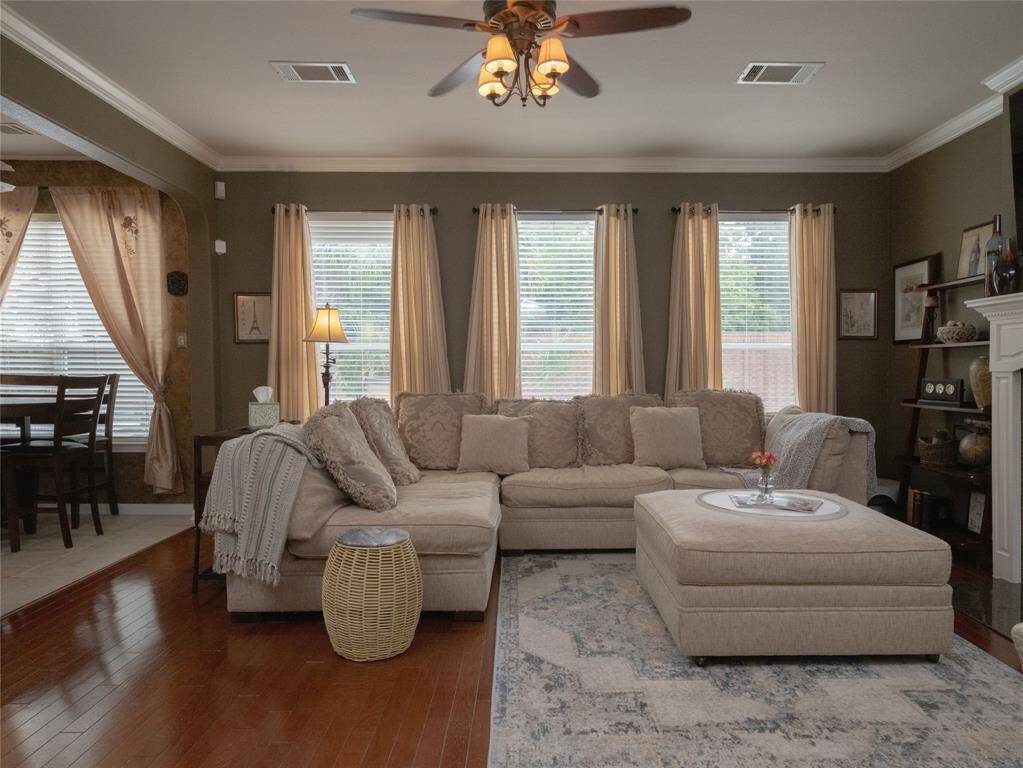 Love how this family room offers lots of natural light streaming through multiple windows with soft curtains. The adjacent breakfast area is visible, enhancing the open, airy feel. Elegant decor and a ceiling fan add charm and comfort.