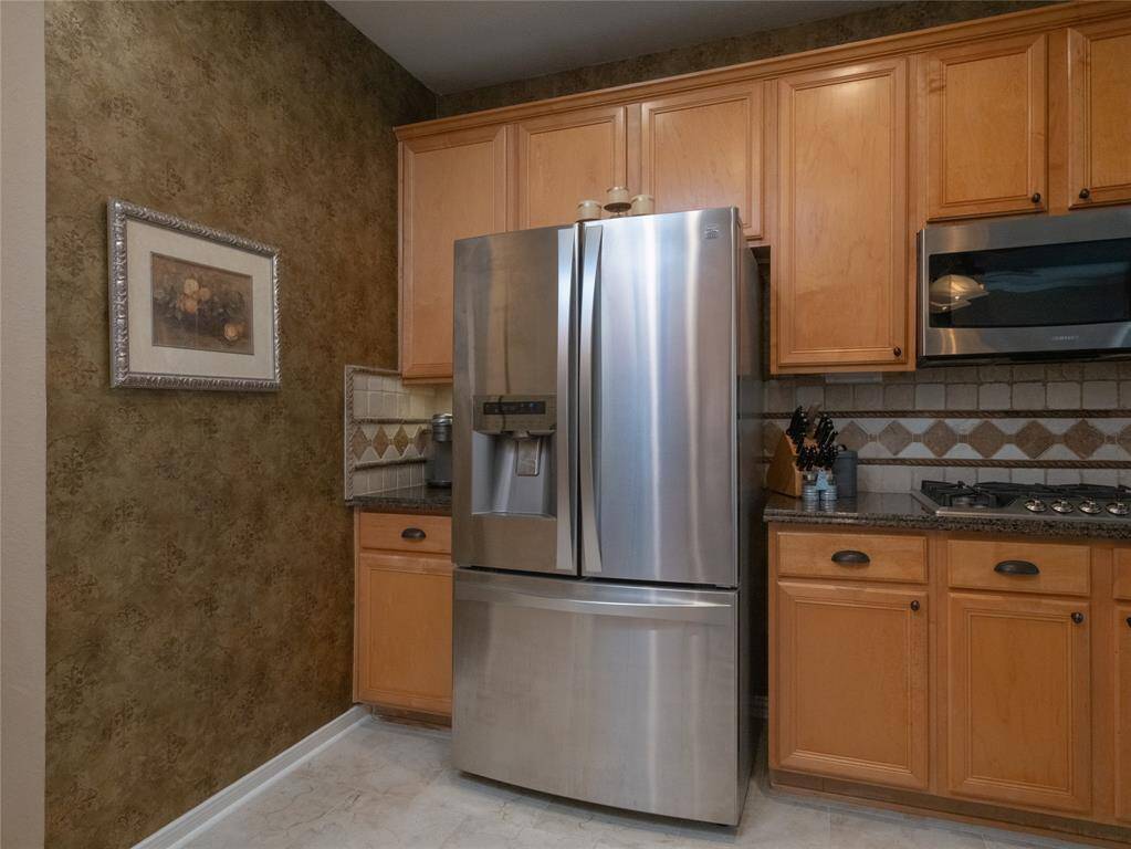 Love this kitchen space with the stainless steel appliances. It has warm wood cabinets, granite countertops, and a decorative tile backsplash, offering a cozy and functional space.