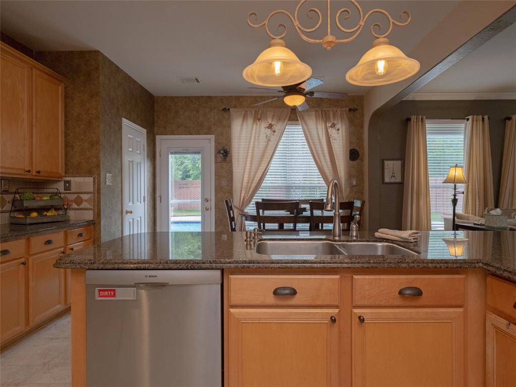 Love the view from the kitchen island with a large sink, and a built-in dishwasher. A cozy breakfast area with a large window offers plenty of natural light and a view of the pool, while a door provides easy access to the backyard. Elegant lighting fixtures add a touch of charm.