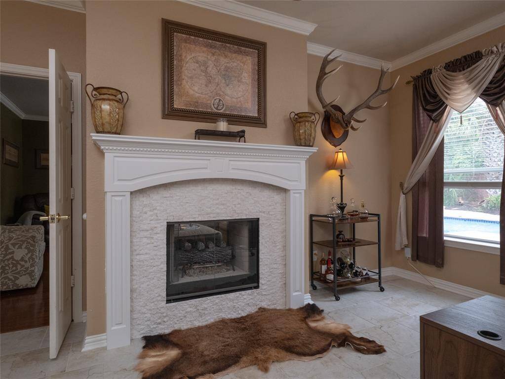 Study or Bonus Room? You pick! Enjoy working in this study or relaxing with a good book with the white stone fireplace, decorative accents, and a window with elegant drapes offering a pool view. Perfect space to work, relax or entertain.