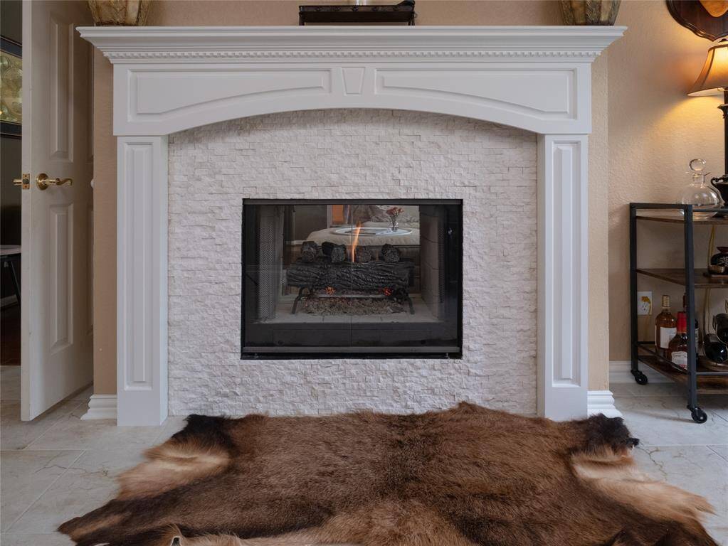 Check out this stylish fireplace in the study/bonus room with white stone surround and elegant molding with the view of the family room on the other side.