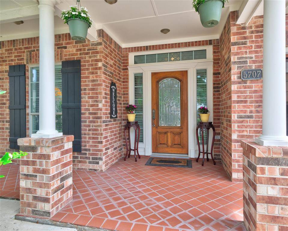 Welcome Home to 5707 Pioneer Ridge Ct! Love this beautiful front porch that is accented by elegant white columns, hanging plants, creating an inviting entrance.