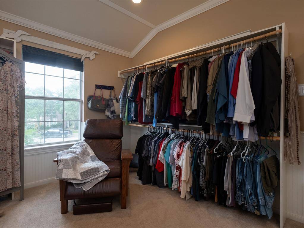 Another view of this Texas sized walk-in closet with ample hanging space for clothes, natural light from a large window.