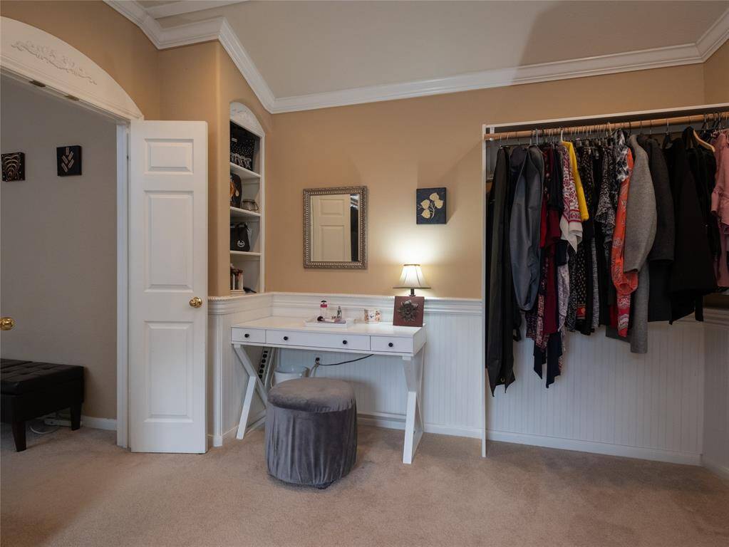 Another view of this Texas sized walk in closet. The space is well-lit and has beige walls with wainscoting, offering a blend of functionality and style.