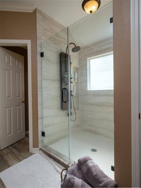 Love this spacious glass-enclosed shower featuring a rainfall showerhead. The space has a clean, neutral design with light-colored walls and flooring.