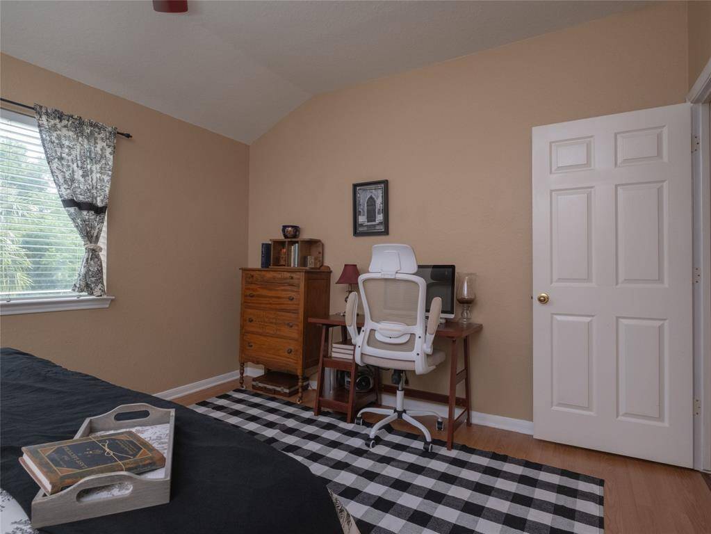 Another view of this bedroom features warm beige walls and wood flooring.