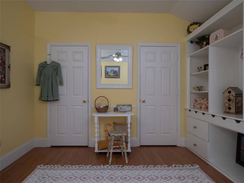 The soft yellow walls, wooden flooring, and a charming setup include two closets for more storage.