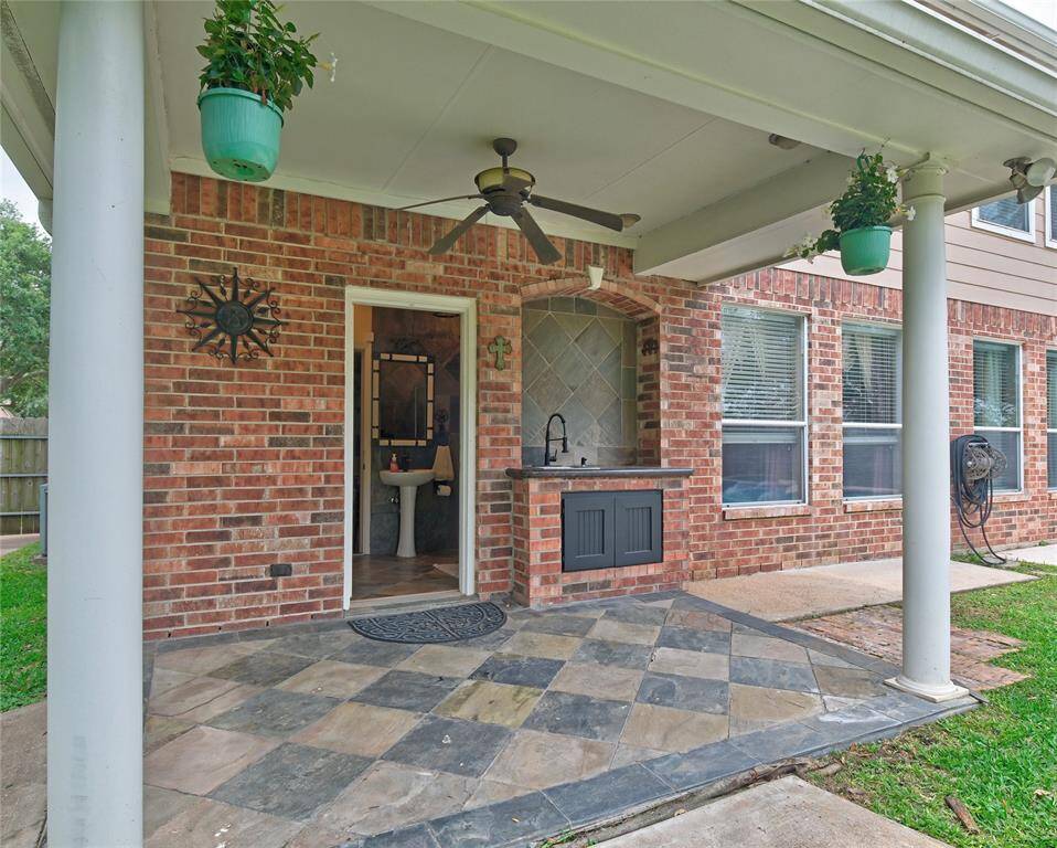 Relax under this outdoor patio with a ceiling fan, tiled flooring, and a built-in sink. The full bathroom is a perfect addition to this pool area!