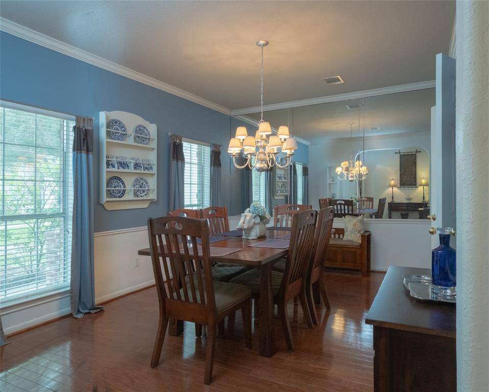 Step into this well designed dining room featuring a warm, inviting atmosphere with hardwood floors and blue walls. Love the mirrored wall accented with beautiful wainscoting walls.