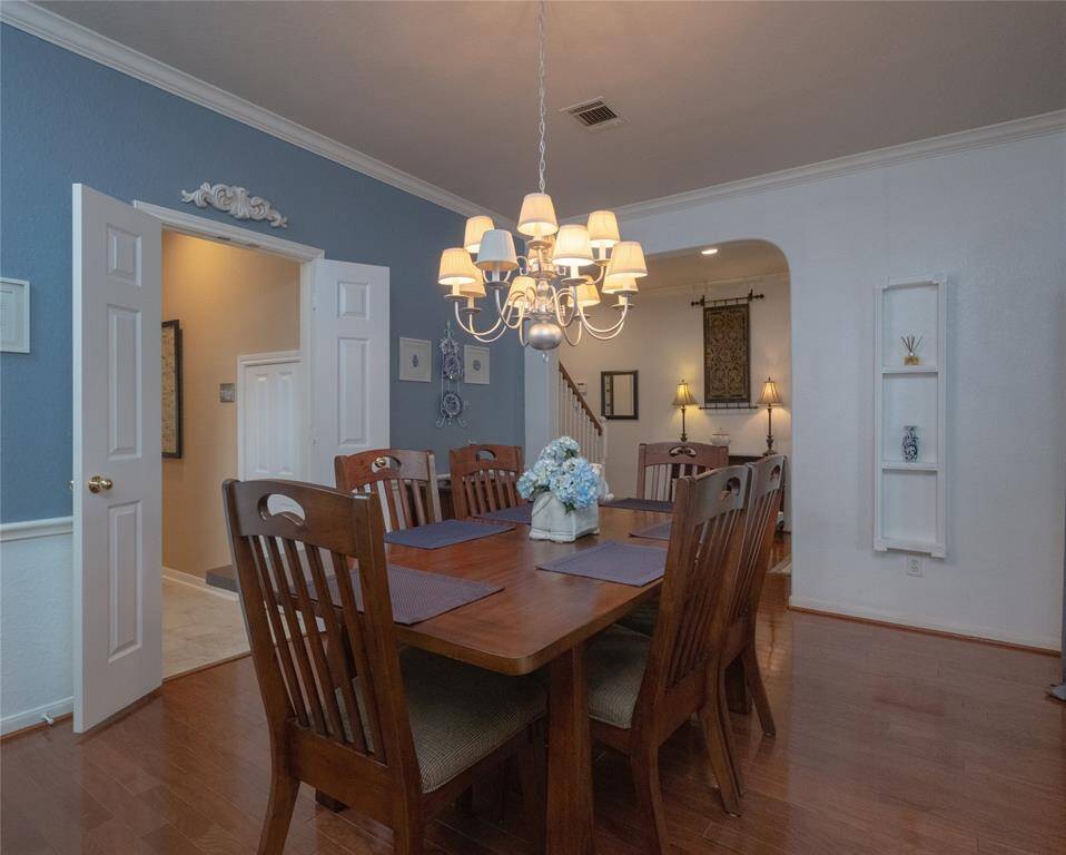 As you can see this dining room features a warm, inviting atmosphere with wooden flooring and a spacious table for eight. A stylish chandelier provides elegant lighting, while the walls are a soothing mix of blue and white. The space connects seamlessly to other areas of the home, offering both functionality and charm.