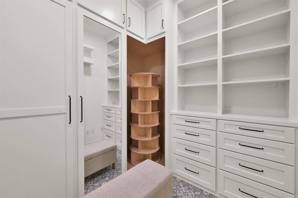 Primary closet is custom built. From beautiful tile work to cedar stripe to show and purse racks to seasonal storage up high. No detail is missed