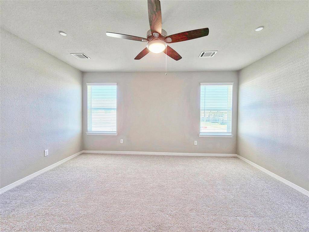 Spacious primary bedroom with ceiling fan and ample natural light