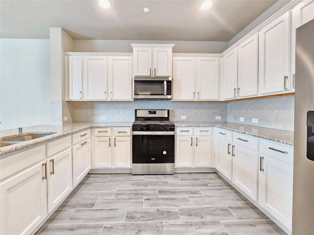 This kitchen is a chef's dream with tons of cabinets and counter space, gas range, built in microwave and stunning white cabinets complemented by granite counter tops and decorative backsplash
