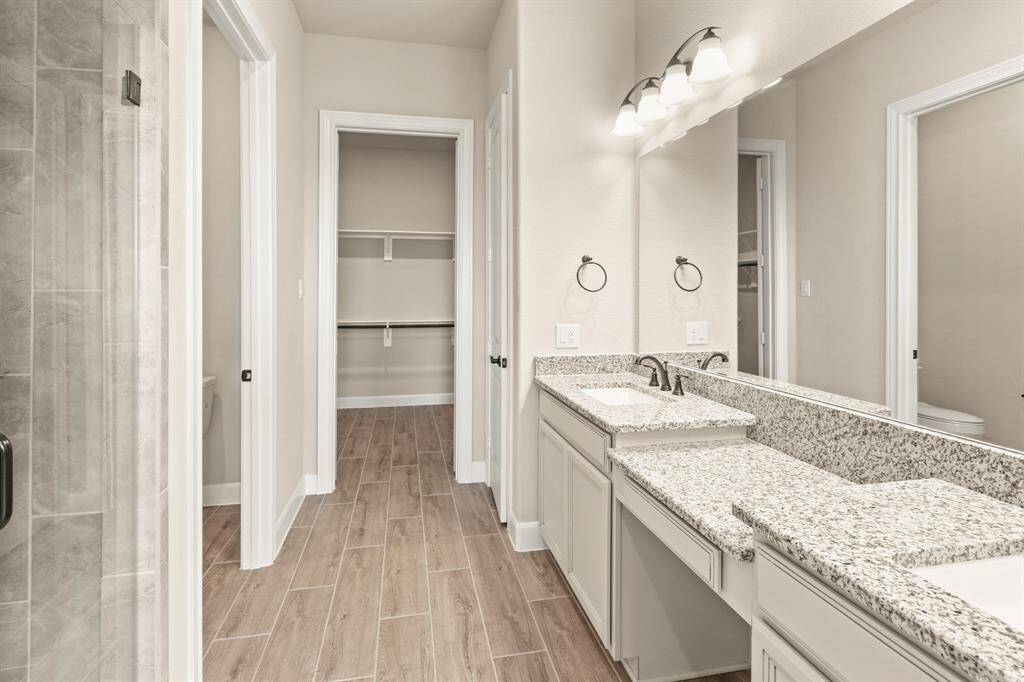 The primary bath features exquisite dual vanities, providing ample personal space along with an abundance of custom cabinetry for seamless organization.