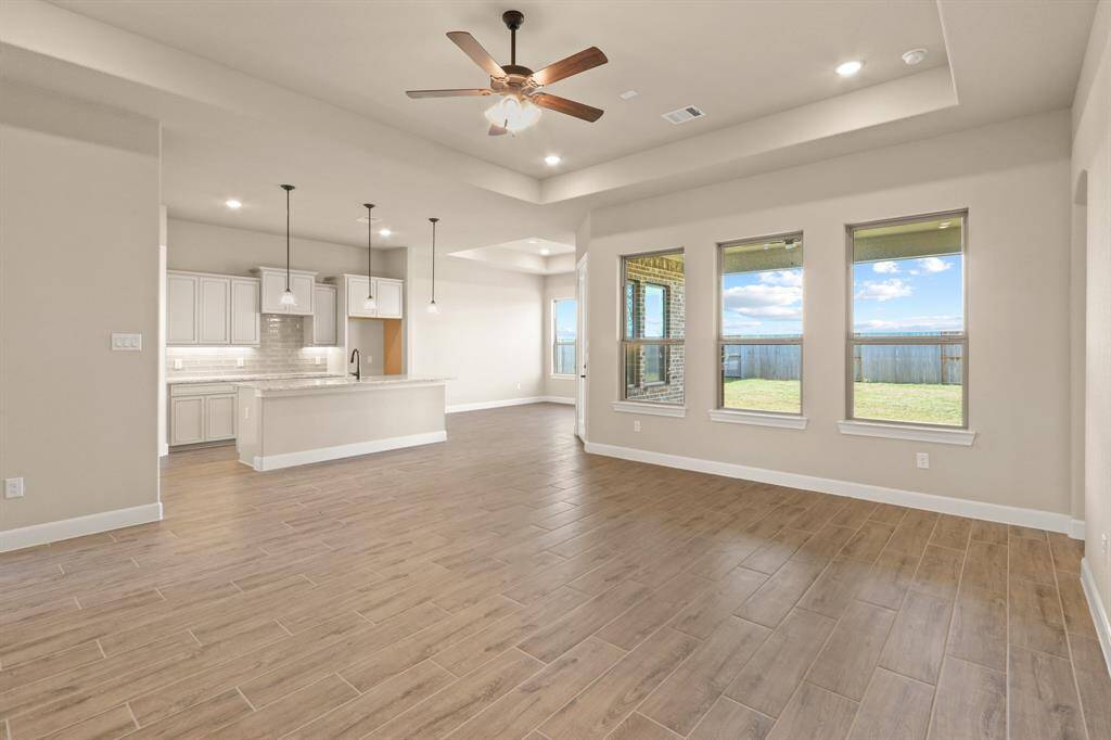 The expansive open-concept living area features a striking wall of windows that flood the space with natural light while offering serene views of the picturesque backyard—creating a perfect blend of indoor comfort and outdoor beauty.