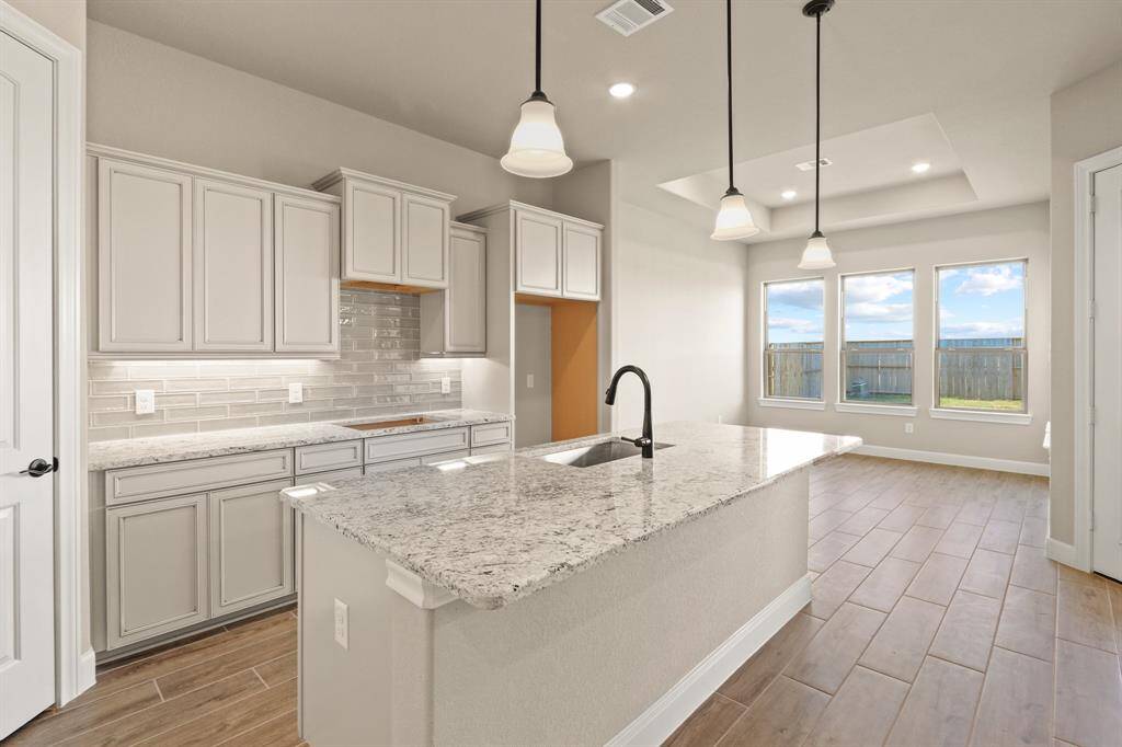 Your chef-inspired kitchen is ready to impress! This beautifully designed space boasts gleaming granite countertops with coordinating tile backsplash. The rich cabinetry  is perfectly complemented by under-cabinet lighting and recessed lighting, creating a bright and inviting ambiance. At the heart of it all, a sprawling island with breakfast bar seating offers the perfect spot for casual dining and entertaining.