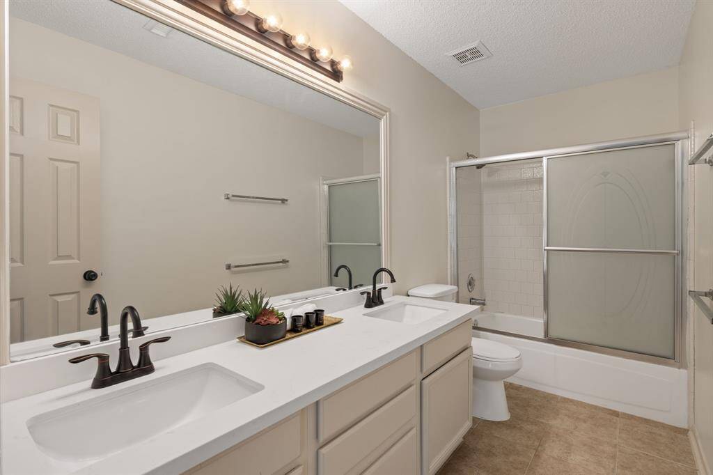 Functional and stylish! This spacious shared bathroom boasts convenient double sinks, a versatile shower/tub combo, and abundant storage for all your essentials.