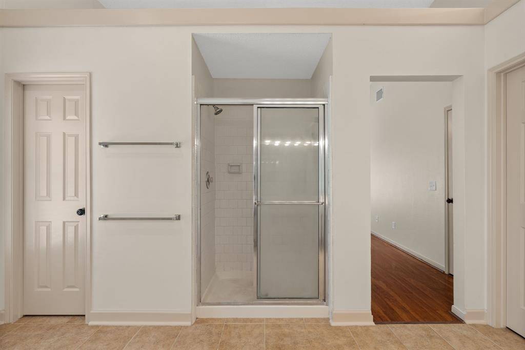 Indulge in this spacious primary bathroom, where high ceilings amplify the sense of luxury. Relax in the jetted tub, enjoy the privacy of a separate toilet, and appreciate the convenience of double sinks and a standing shower. The soothing beige palette creates a spa-like retreat.