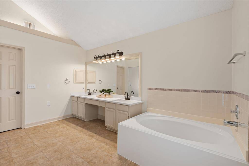 Indulge in this spacious primary bathroom, where high ceilings amplify the sense of luxury. Relax in the jetted tub, enjoy the privacy of a separate toilet, and appreciate the convenience of double sinks and a standing shower. The soothing beige palette creates a spa-like retreat.