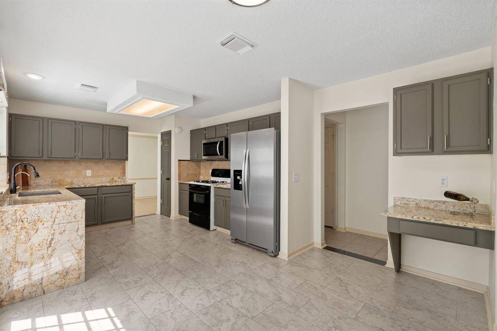 Step into this beautifully updated kitchen, boasting gleaming granite countertops and refreshed walls and cabinets. Generously sized, it offers space for a portable island, a built-in secretary desk, and a charming kitchenette nook.