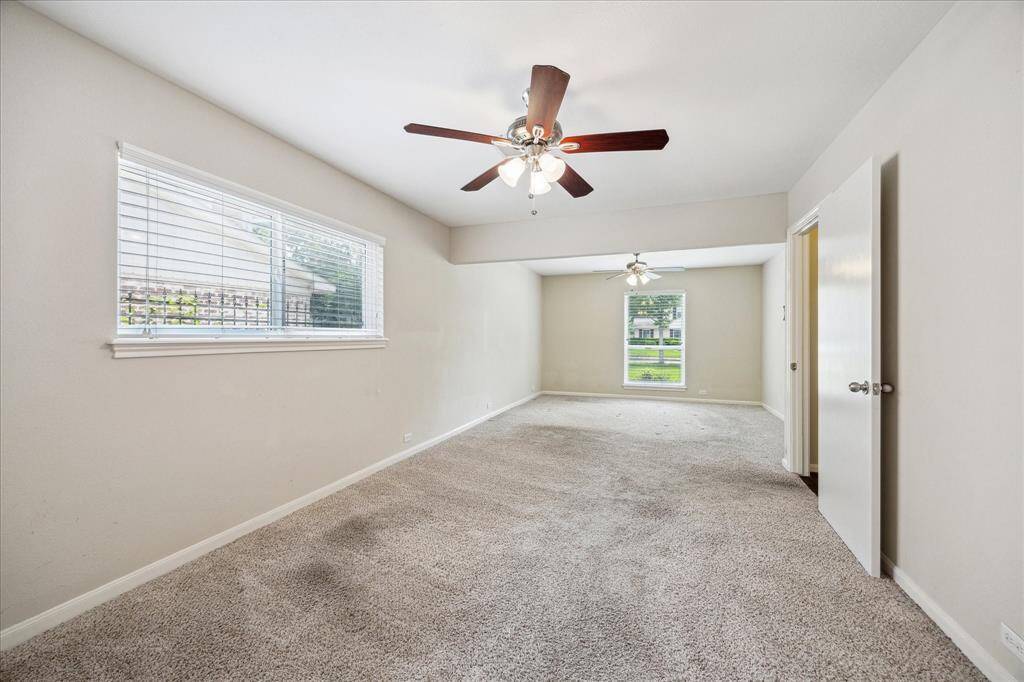 The oversized first-floor primary suite features a sitting area and dual ceiling fans, and adjoins the remodeled primary bath.