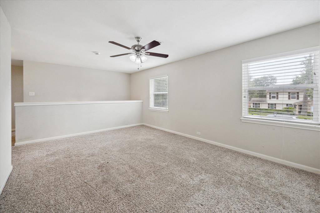 Upstairs gameroom with neutral carpet, ceiling fan, and natural light - perfect for a playroom, home office, or second living space.