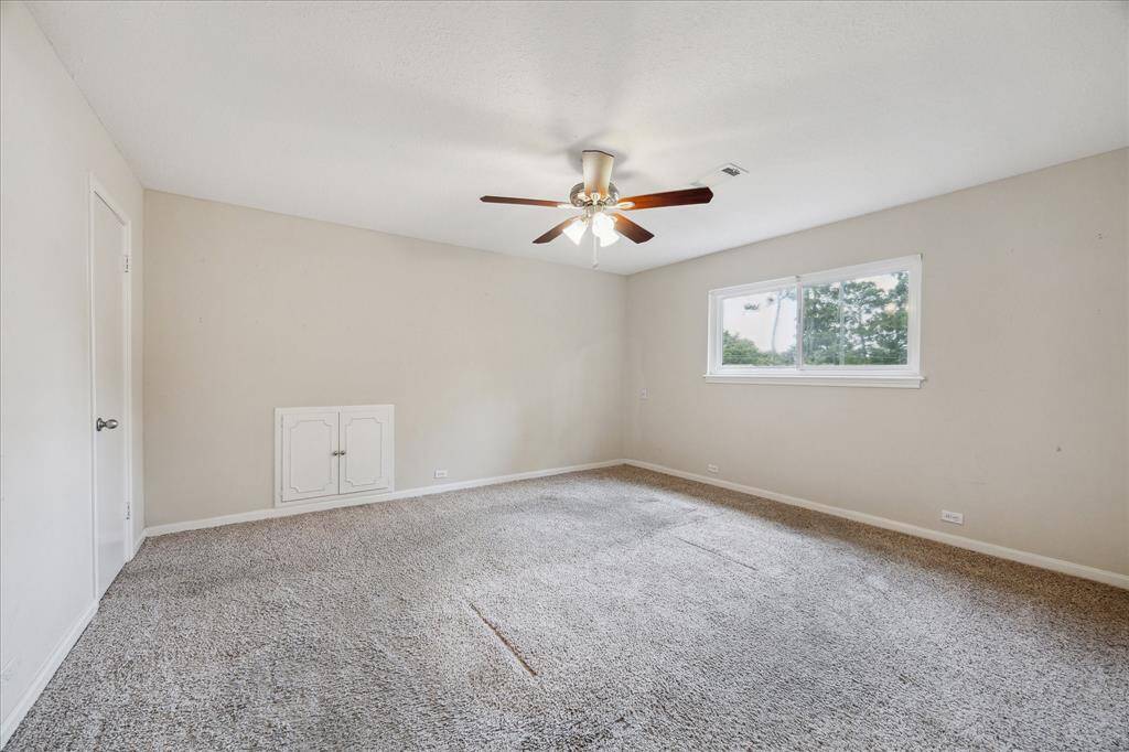 Secondary bedroom with neutral carpet, walk-in closet, and lighted ceiling fan.