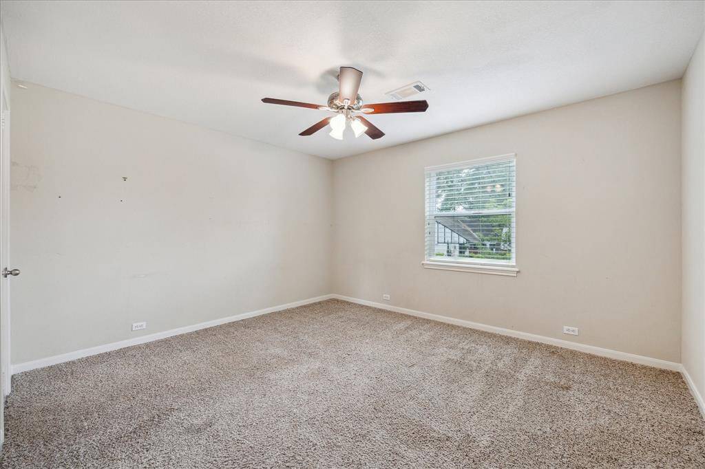 Secondary bedroom with neutral carpet, walk-in closet, and lighted ceiling fan.